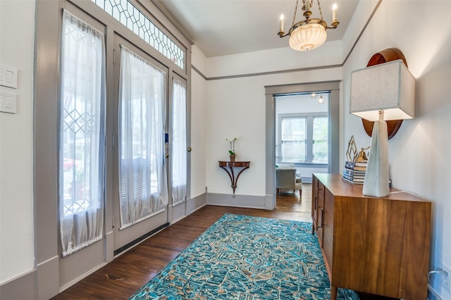 entryway with a chandelier, baseboards, and dark wood-style floors