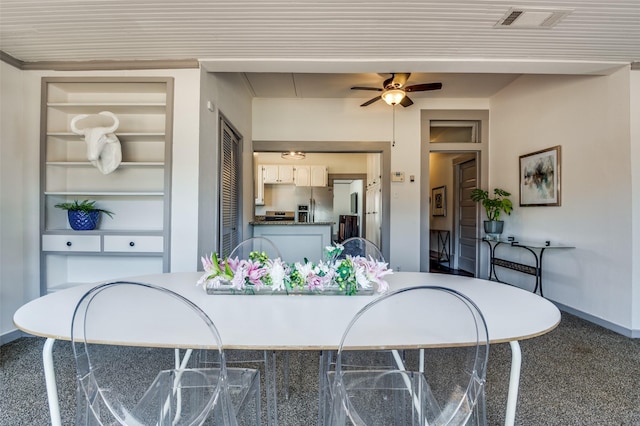 kitchen featuring dark countertops, visible vents, built in shelves, baseboards, and ceiling fan