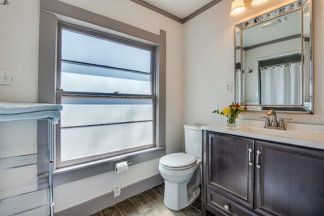 bathroom with vanity, wood finished floors, baseboards, crown molding, and toilet