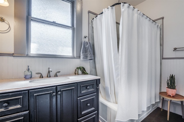 full bathroom featuring vanity, shower / bath combo with shower curtain, and a wainscoted wall