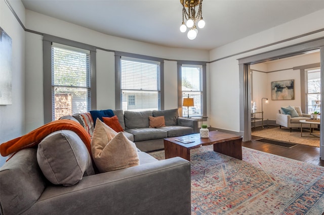 living room featuring a chandelier, baseboards, and wood finished floors