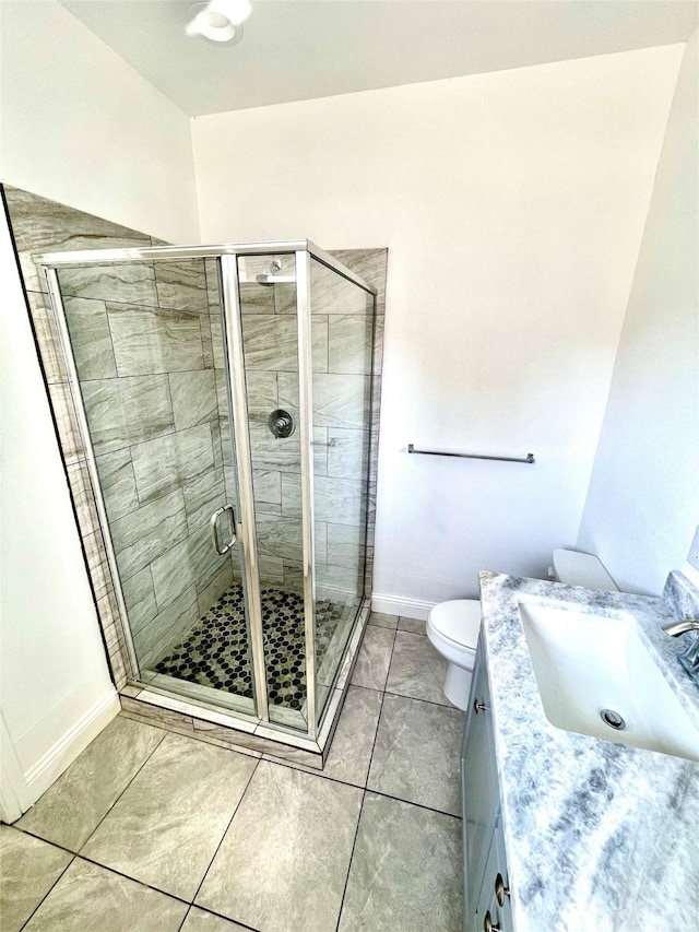 full bathroom featuring toilet, a shower stall, tile patterned flooring, baseboards, and vanity