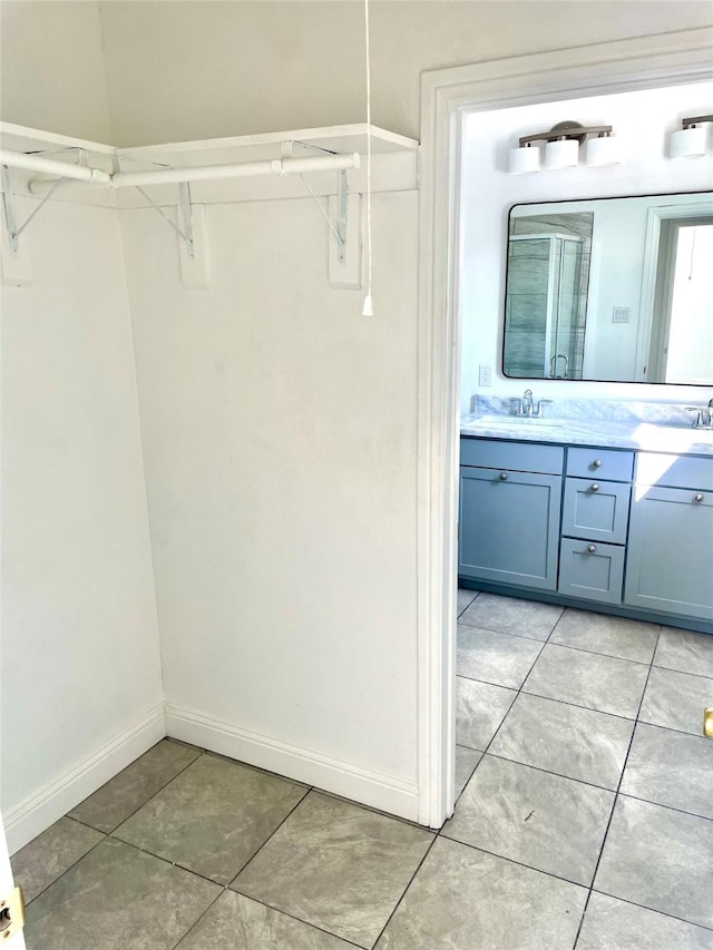 bathroom featuring double vanity, baseboards, tile patterned floors, and a sink