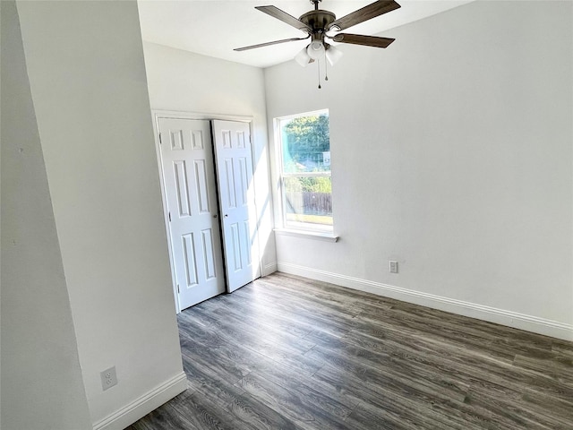 unfurnished bedroom with dark wood finished floors, ceiling fan, a closet, and baseboards