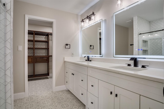 full bathroom with double vanity, tiled shower, a walk in closet, and a sink