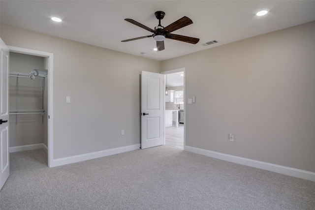 unfurnished bedroom featuring visible vents, baseboards, light colored carpet, and a spacious closet