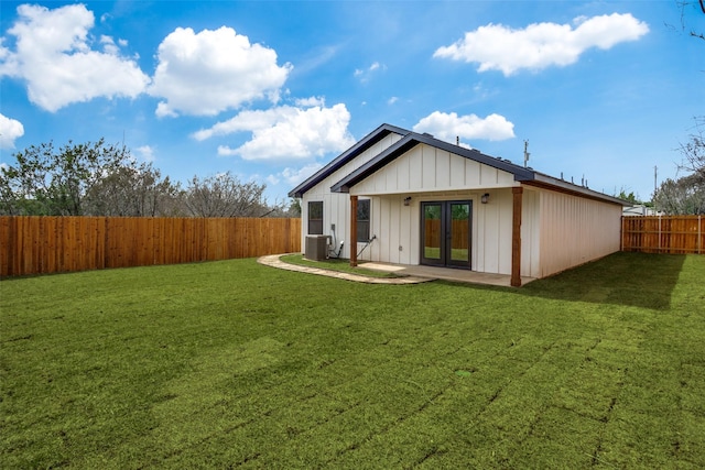 rear view of house with french doors, a lawn, central AC unit, and a fenced backyard