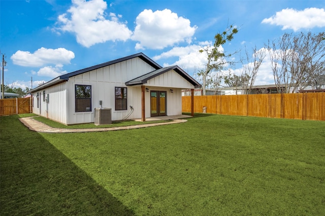 back of property featuring board and batten siding, central AC, french doors, a yard, and a fenced backyard