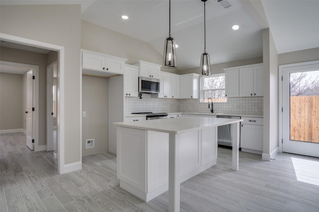 kitchen featuring a kitchen island, light countertops, lofted ceiling, light wood-type flooring, and stainless steel appliances