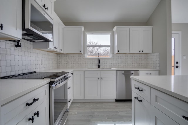 kitchen featuring light countertops, white cabinets, appliances with stainless steel finishes, and a sink