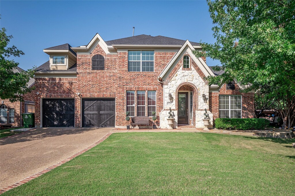 view of front of home featuring brick siding, driveway, an attached garage, and a front yard