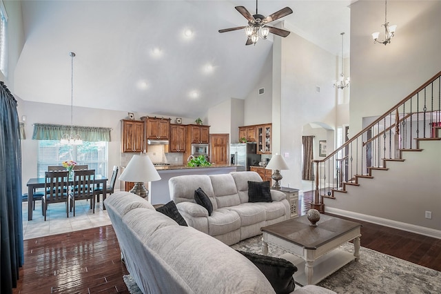 living area featuring baseboards, stairs, ceiling fan with notable chandelier, arched walkways, and dark wood-style flooring