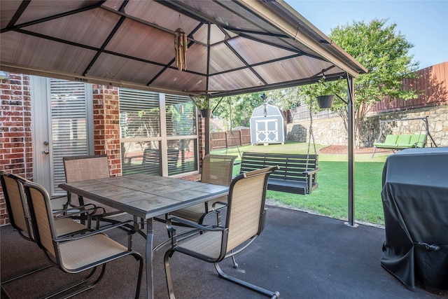 view of patio / terrace featuring outdoor dining space, an outbuilding, a fenced backyard, a gazebo, and a storage unit