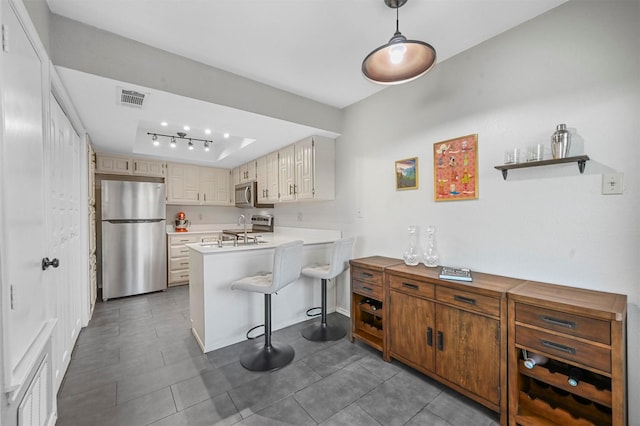 kitchen with visible vents, a kitchen bar, light countertops, a peninsula, and stainless steel appliances