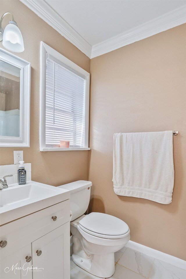 bathroom with vanity, baseboards, crown molding, toilet, and marble finish floor