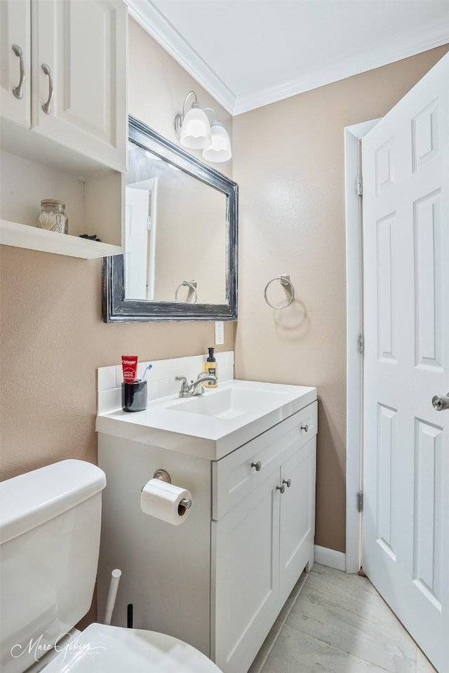 half bathroom featuring vanity, toilet, crown molding, and baseboards