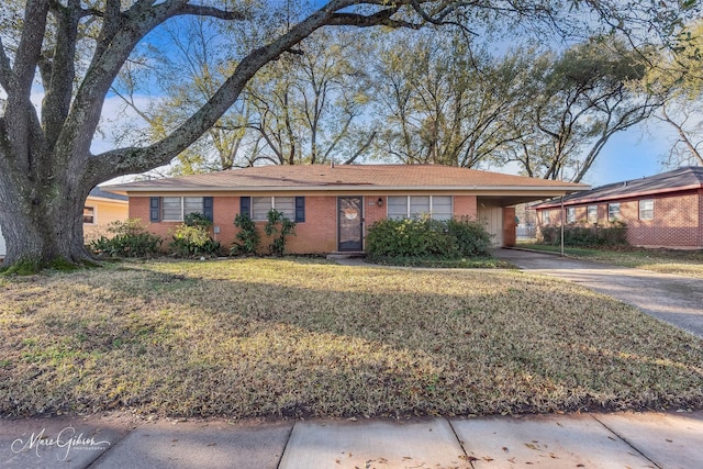 ranch-style house featuring a front lawn, brick siding, concrete driveway, and a carport