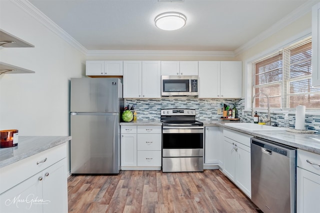 kitchen featuring backsplash, light wood-style flooring, appliances with stainless steel finishes, and a sink