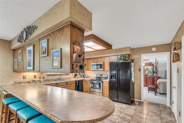 kitchen with a kitchen breakfast bar, a textured ceiling, stainless steel appliances, a peninsula, and light countertops