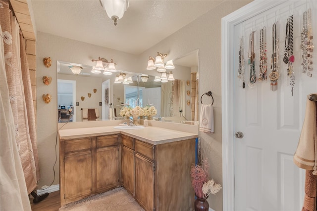 bathroom with vanity, a textured wall, and a textured ceiling