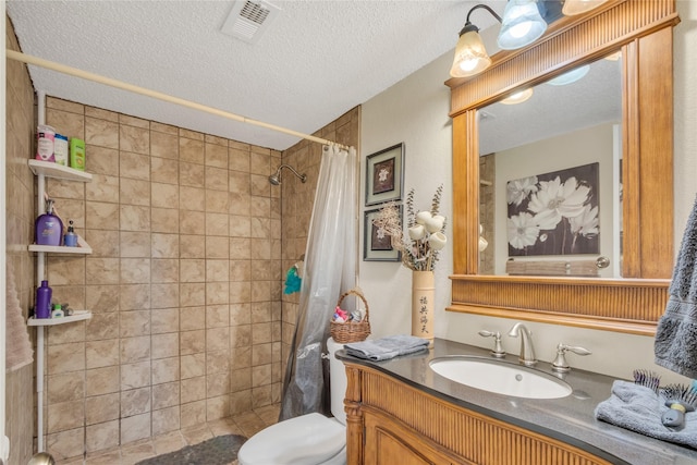 bathroom featuring visible vents, toilet, a textured ceiling, a tile shower, and vanity