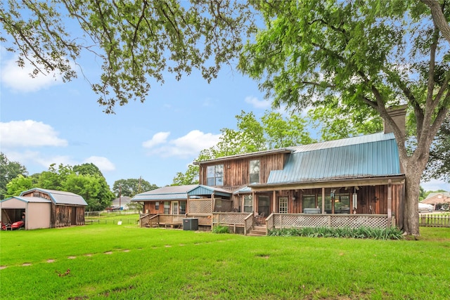 rear view of house featuring an outbuilding, central AC unit, a yard, a sunroom, and metal roof