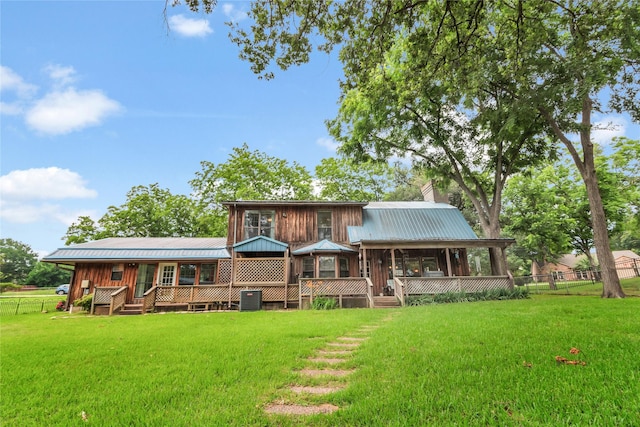 back of property featuring central air condition unit, a yard, a sunroom, metal roof, and a chimney