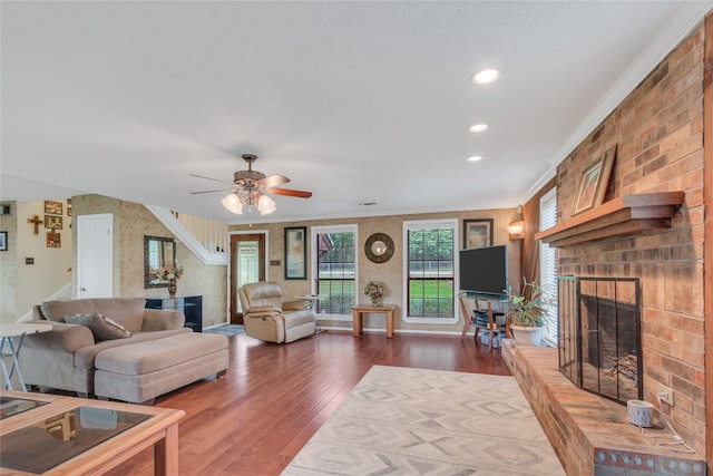 living room with wood finished floors, recessed lighting, a fireplace, crown molding, and baseboards