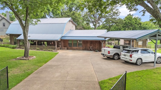 country-style home with driveway, fence, a front yard, metal roof, and a carport