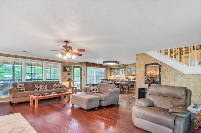 living room with visible vents, a textured ceiling, wood finished floors, and wallpapered walls