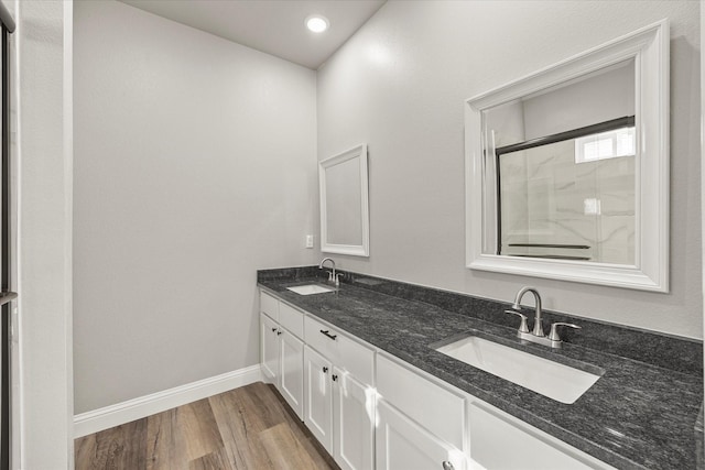 full bath with wood finished floors, baseboards, a shower with door, and a sink