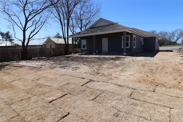 exterior space with a shingled roof and fence