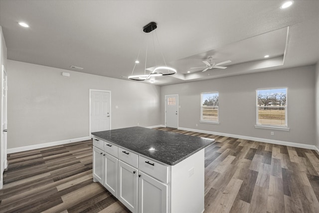 kitchen with open floor plan, white cabinetry, a raised ceiling, and baseboards