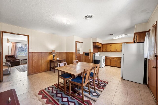 dining room with light tile patterned floors, wainscoting, visible vents, and a textured ceiling