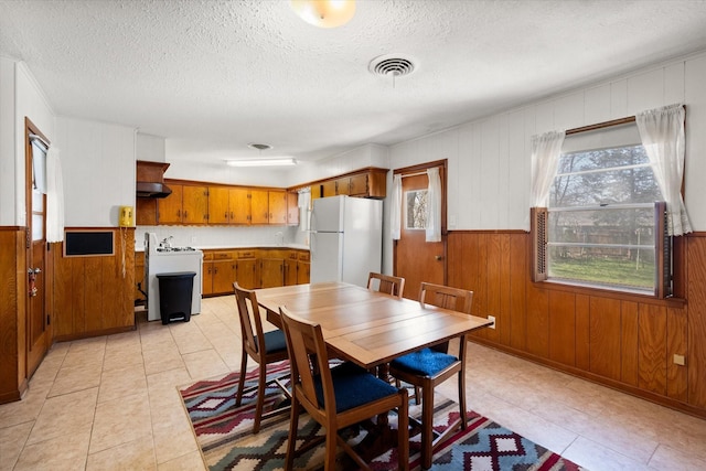 dining space with visible vents, plenty of natural light, a textured ceiling, and wooden walls