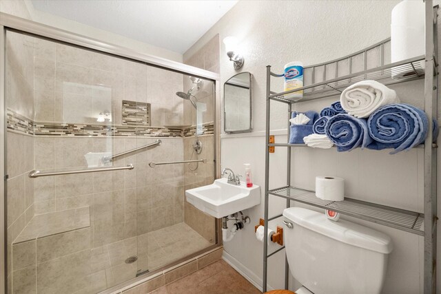 full bath with a sink, toilet, a stall shower, and tile patterned flooring