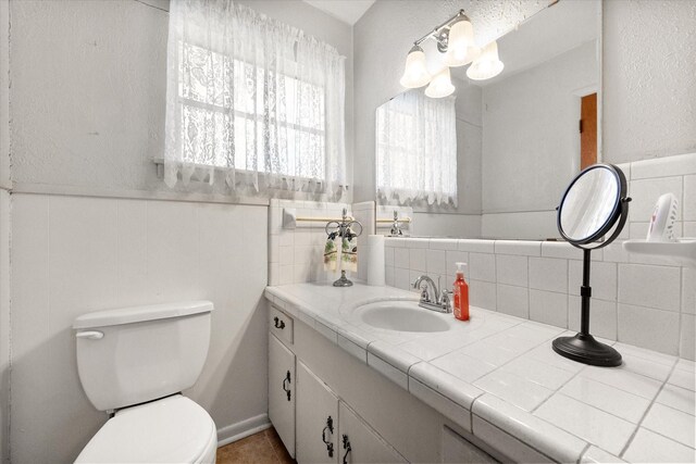 bathroom with a wainscoted wall, toilet, and vanity