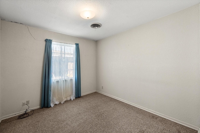 unfurnished room with visible vents, a textured ceiling, baseboards, and carpet floors