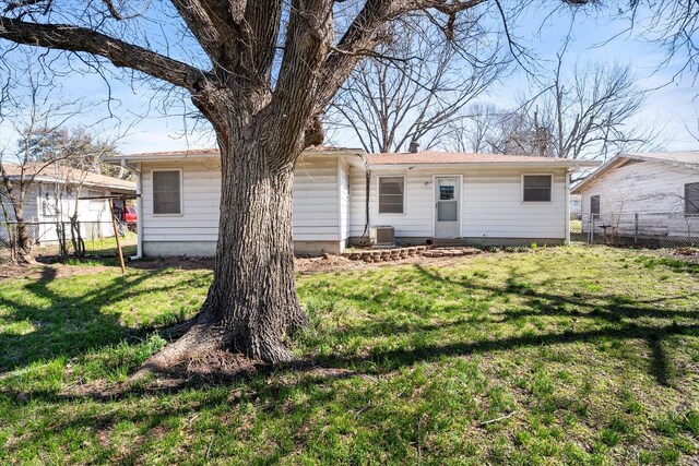 back of property with a lawn, central AC, a chimney, and fence