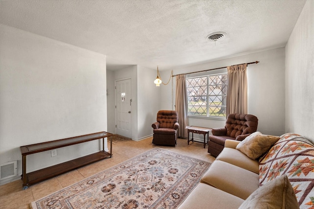 living room featuring light tile patterned floors, visible vents, baseboards, and a textured ceiling