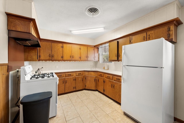 kitchen featuring white appliances, light countertops, visible vents, and brown cabinets