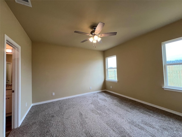 carpeted empty room with visible vents, baseboards, and a ceiling fan