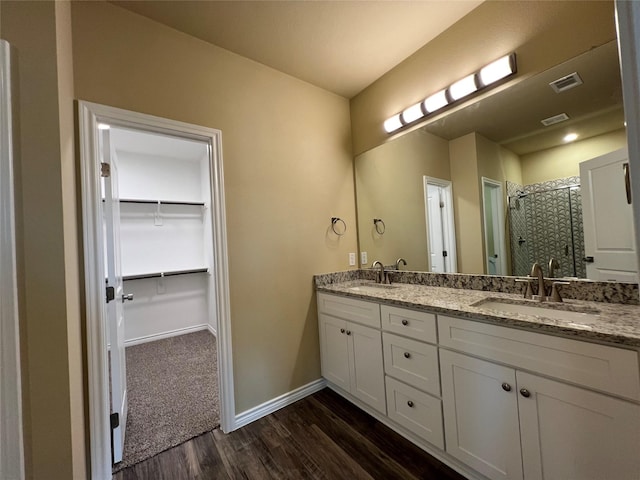 full bath featuring wood finished floors, baseboards, visible vents, a stall shower, and a sink