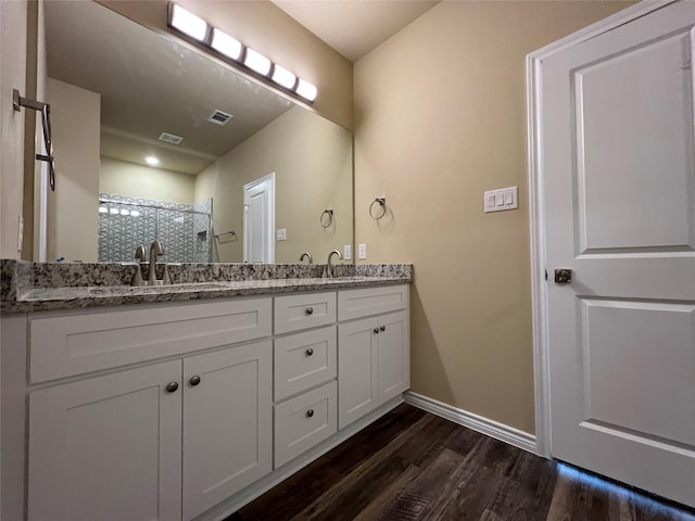 bathroom with a sink, wood finished floors, a stall shower, and double vanity