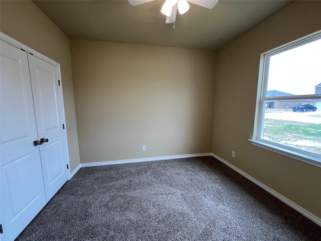 unfurnished bedroom featuring a closet, baseboards, a ceiling fan, and dark carpet