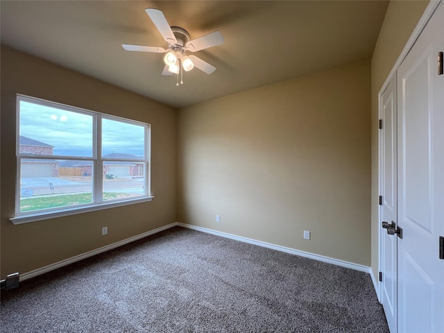 unfurnished bedroom with a closet, baseboards, a ceiling fan, and dark carpet