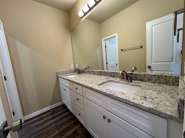 bathroom featuring double vanity, wood finished floors, baseboards, and a sink