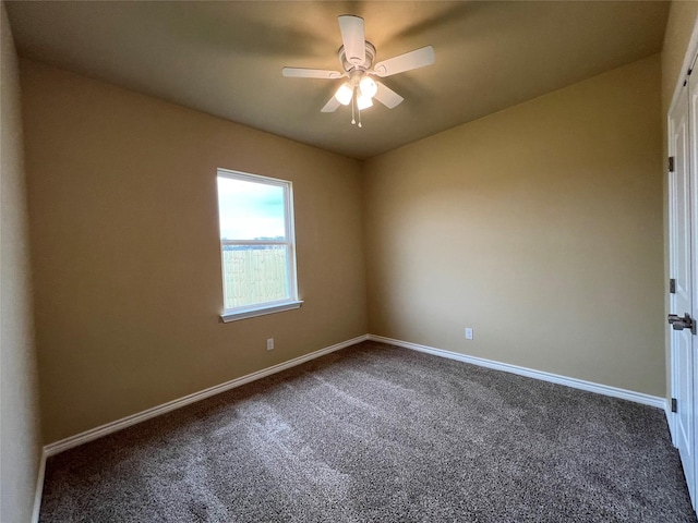 empty room featuring baseboards, dark carpet, and ceiling fan