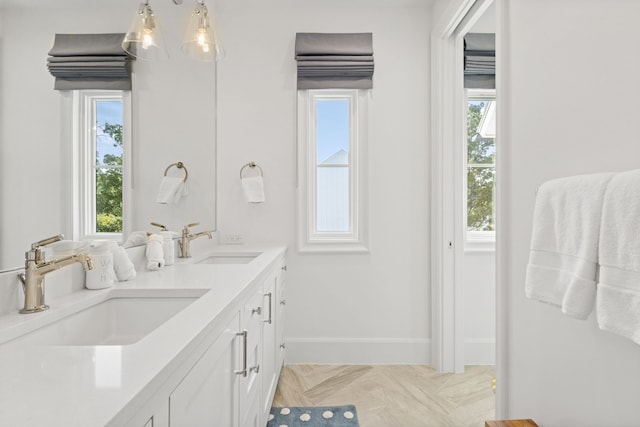 bathroom with a sink, baseboards, a notable chandelier, and double vanity