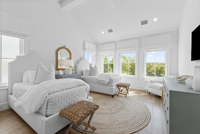 bedroom with visible vents, baseboards, beam ceiling, light wood-style flooring, and high vaulted ceiling